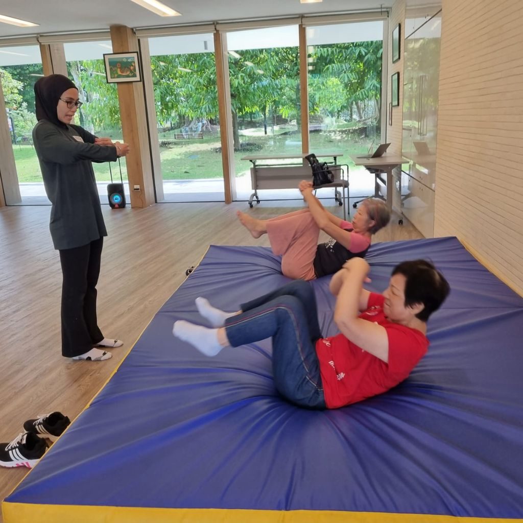 Seniors practising safe rolling on a crash mat with an E3Sports trainer at a Rolling Good Times falls prevention session